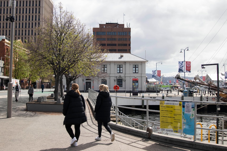 Mask-wearing pedestrians walk past the docks.