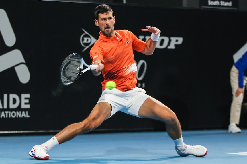 A Serbian male professional tennis player stretches to play a forehand.