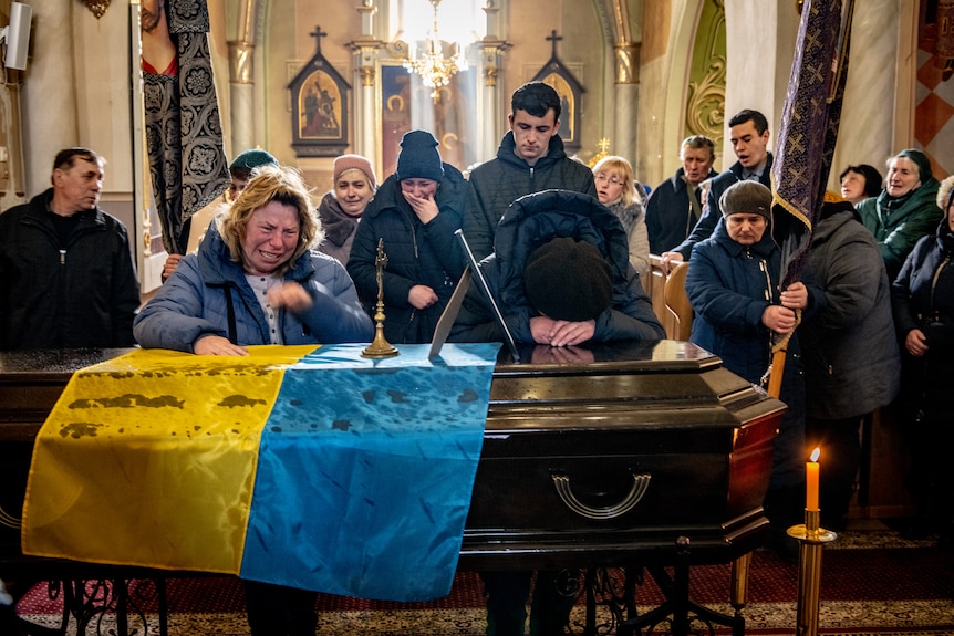 The family leans on his casket. 