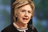 Hillary Clinton speaks in front of a microphone while looking into the distance.