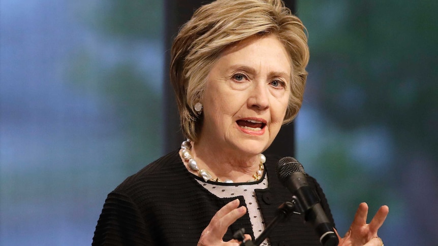 Hillary Clinton speaks in front of a microphone while looking into the distance.