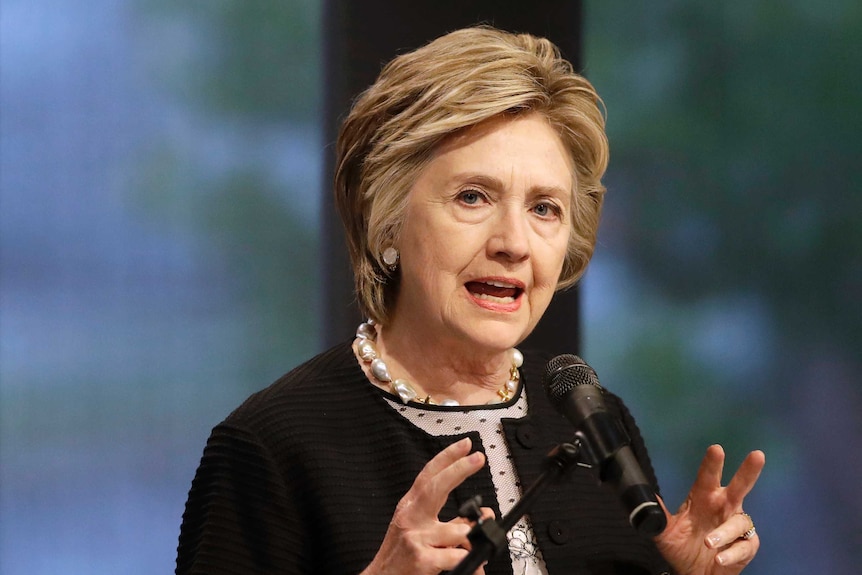 Hillary Clinton speaks in front of a microphone while looking into the distance.