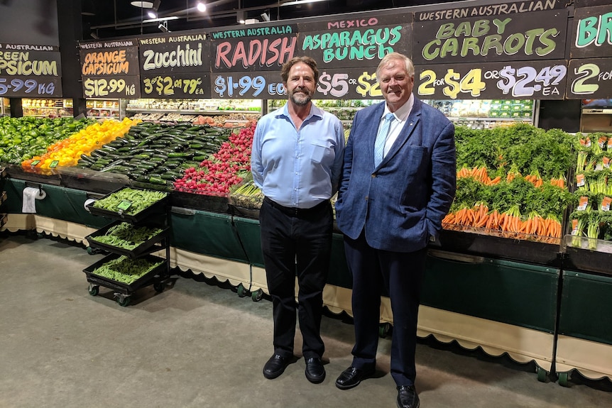 Two men standing in front of a fruit and vegetable aisle in farmers market