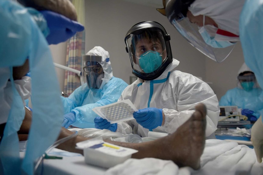 healthcare workers wearing PPE treat a patient infected with coronavirus