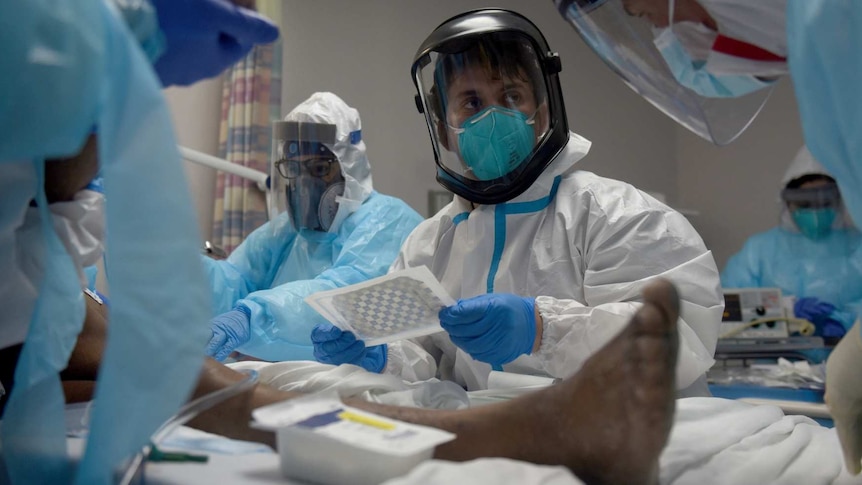 healthcare workers wearing PPE treat a patient infected with coronavirus