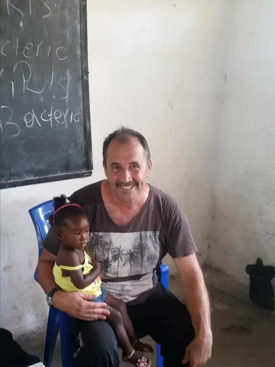 Mick Fernandez sits with a child on his lap inside a classroom in Liberia.