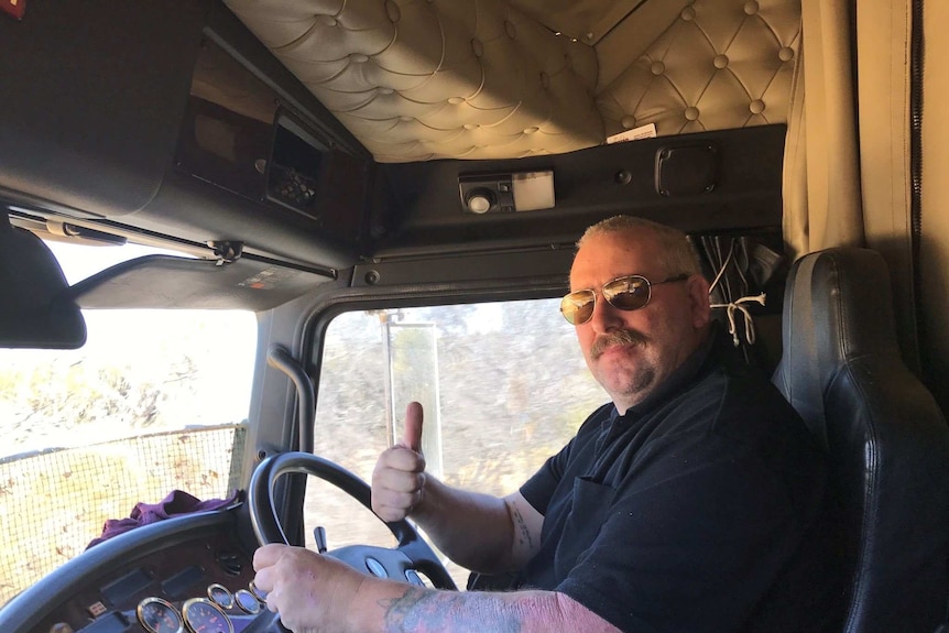 A truck driver offers the thumbs-up sign from his cab