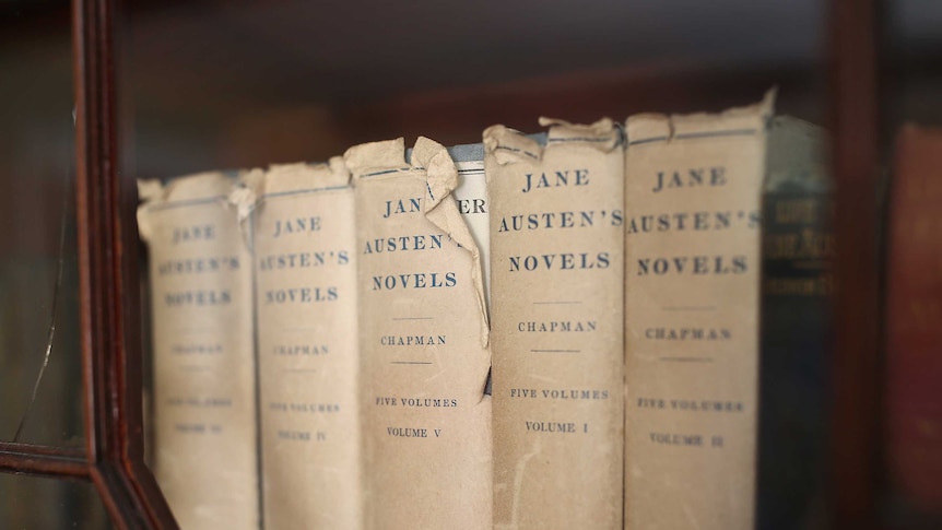 A line of Jane Austen's complete works, aged and worn books.