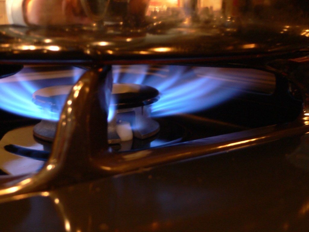 Primer plano de la llama azul de una estufa de gas encendida.