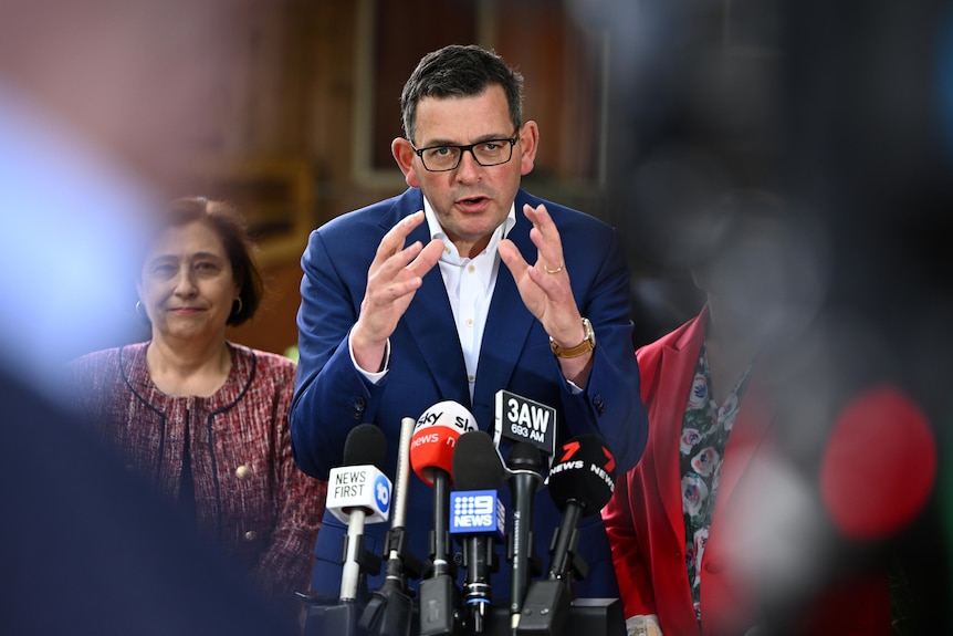 Daniel Andrews holds his hands out while speaking at a media conference.