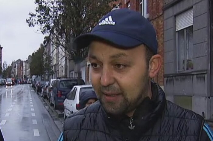 Hotel worker Wadii Berrada stands in a rainy street in Molenbeek, a suburb of Brussels, wearing a blue Adidas cap