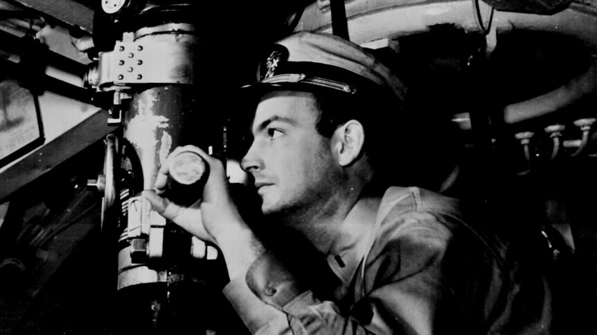 A United States naval officer looks through a periscope.