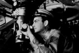 A United States naval officer looks through a periscope.