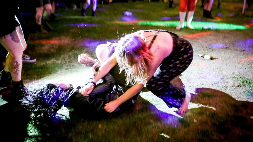 Two women tussle on the grass at night