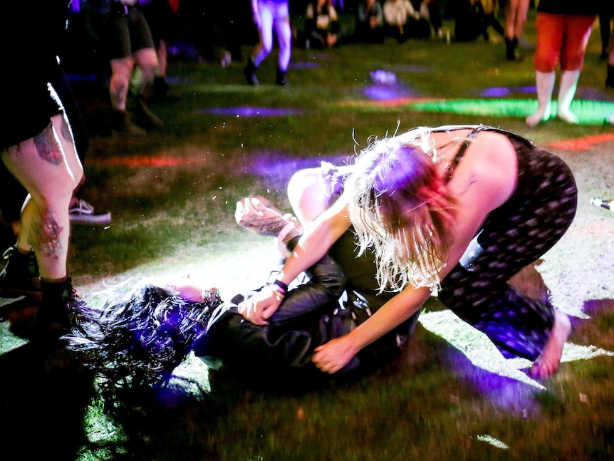 Two women tussle on the grass at night