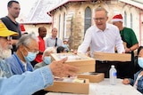 Anthony Albanese in a white shirt hands out lunch to people at a table at Rev Bill Crews in Sydney