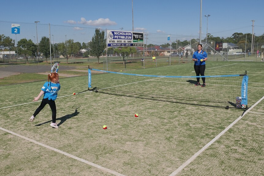 A young girl hitting a tennis ball over a net