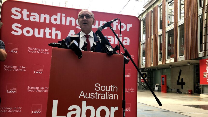 Jay Weatherill standing at a red South Australian Labor podium announcing a policy.