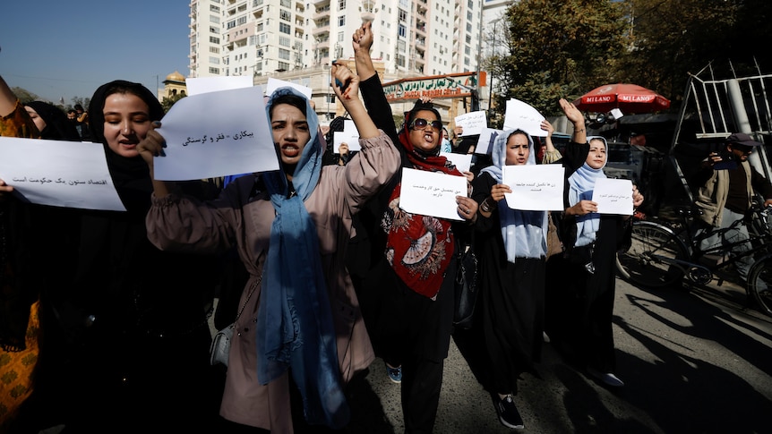 A group of women hold signs and shout on the streets of Kabul. 