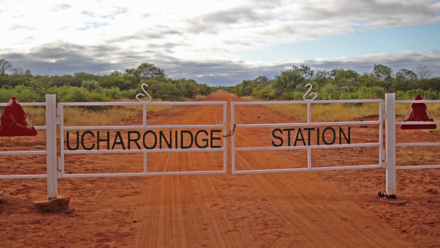 a white gate, reading Ucharonidge Station with a road and bushes in the background.