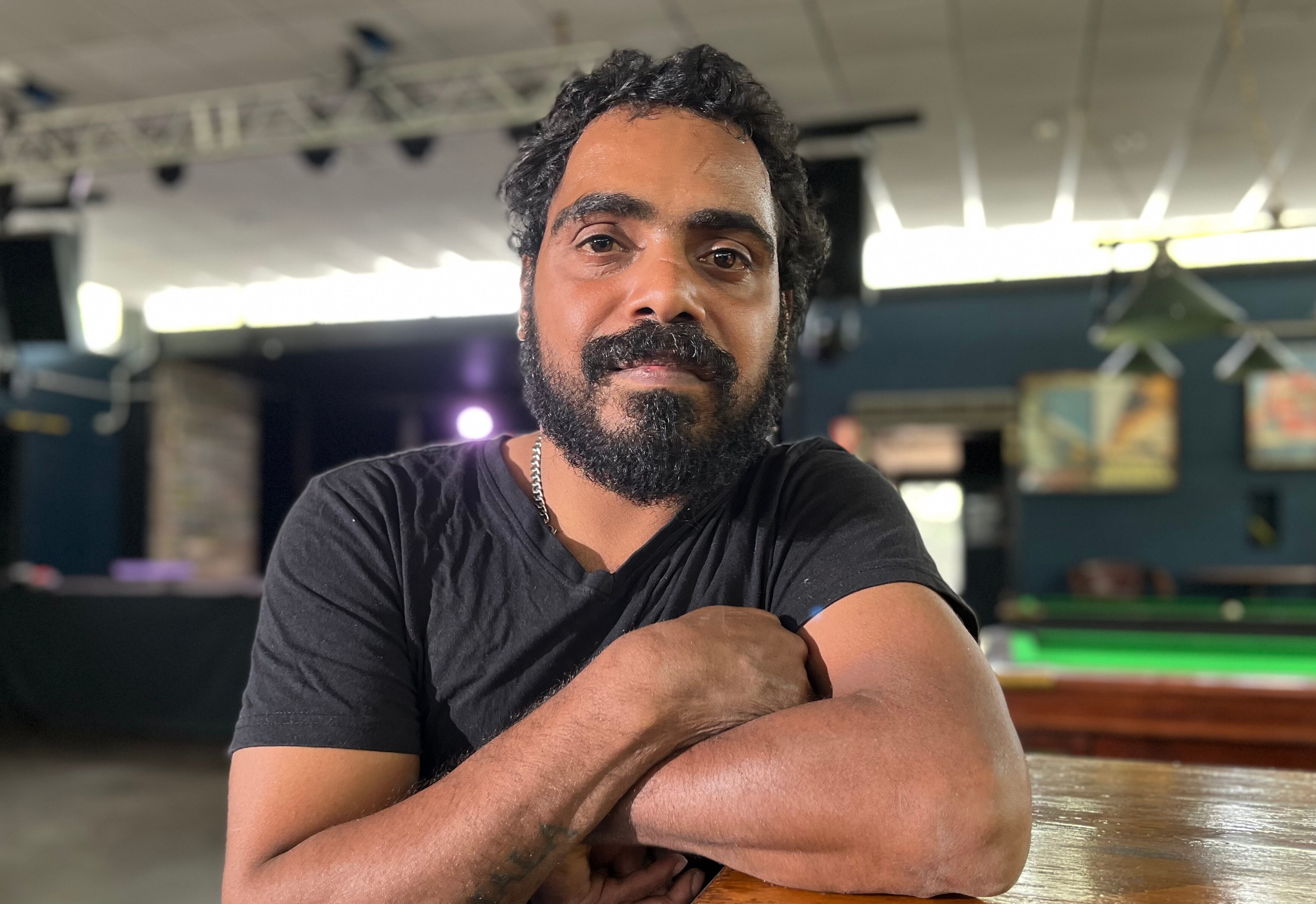 Richie Guymala from the Arnhem Land-based Black Rock Band with arms crossed sitting in a pub.