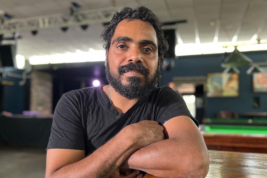 Richie Guymala from the Arnhem Land-based Black Rock Band with arms crossed sitting in a pub.