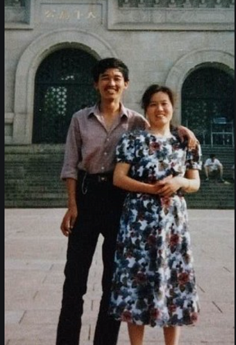 A Chinese man puts his arm around a Chinese women in front of a historical building