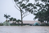 The roofline of a flooded home is visible in a large body of water.