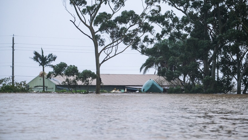 The roofline of a flooded home is visible in a large body of water.