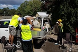Volunteers load the back of a ute with rubbish cleared from a flooded home
