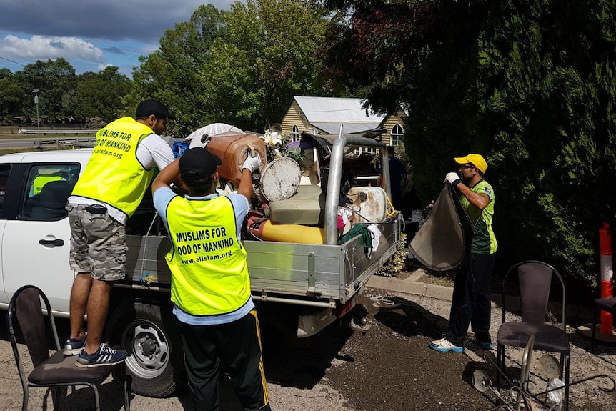 Volunteers load the back of a ute with rubbish cleared from a flooded home