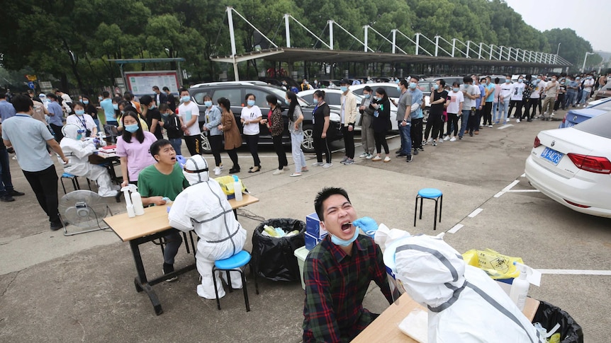 Workers line up for medical workers to take swabs for the coronavirus test at a large factory in Wuhan.