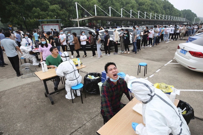 Workers line up for medical workers to take swabs for the coronavirus test at a large factory in Wuhan.