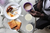 a man's hands eating breakfast and cup of tea