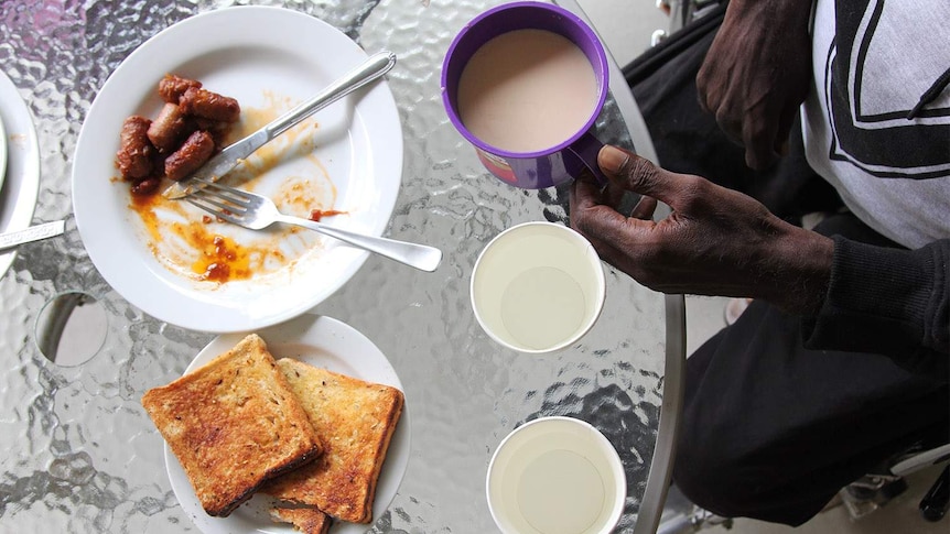 a man's hands eating breakfast and cup of tea