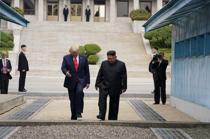 Donald Trump looks at the ground and gesticulates with one hand, left, with Kim Jong-un, right, as they enter South Korea.