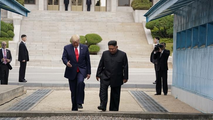 Donald Trump looks at the ground and gesticulates with one hand, left, with Kim Jong-un, right, as they enter South Korea.