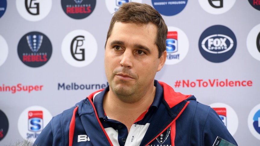 Rugby union coach talking during a press conference.