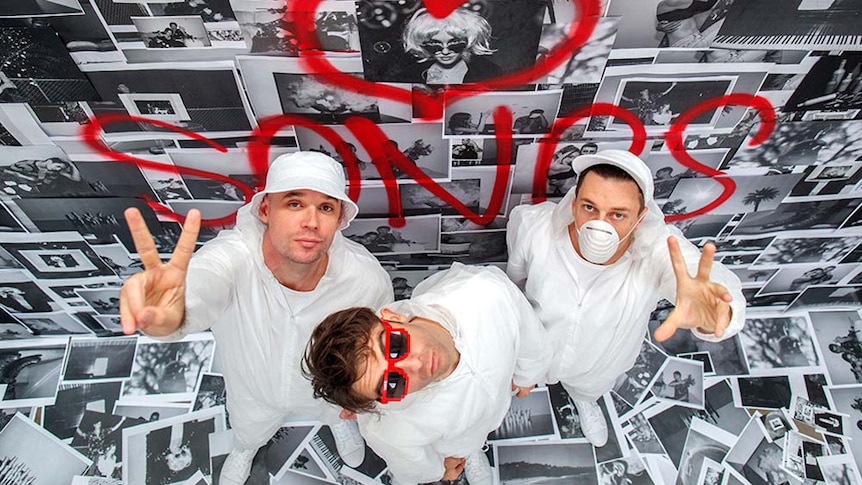 Thundamentals dressed in white against wall of black and white images