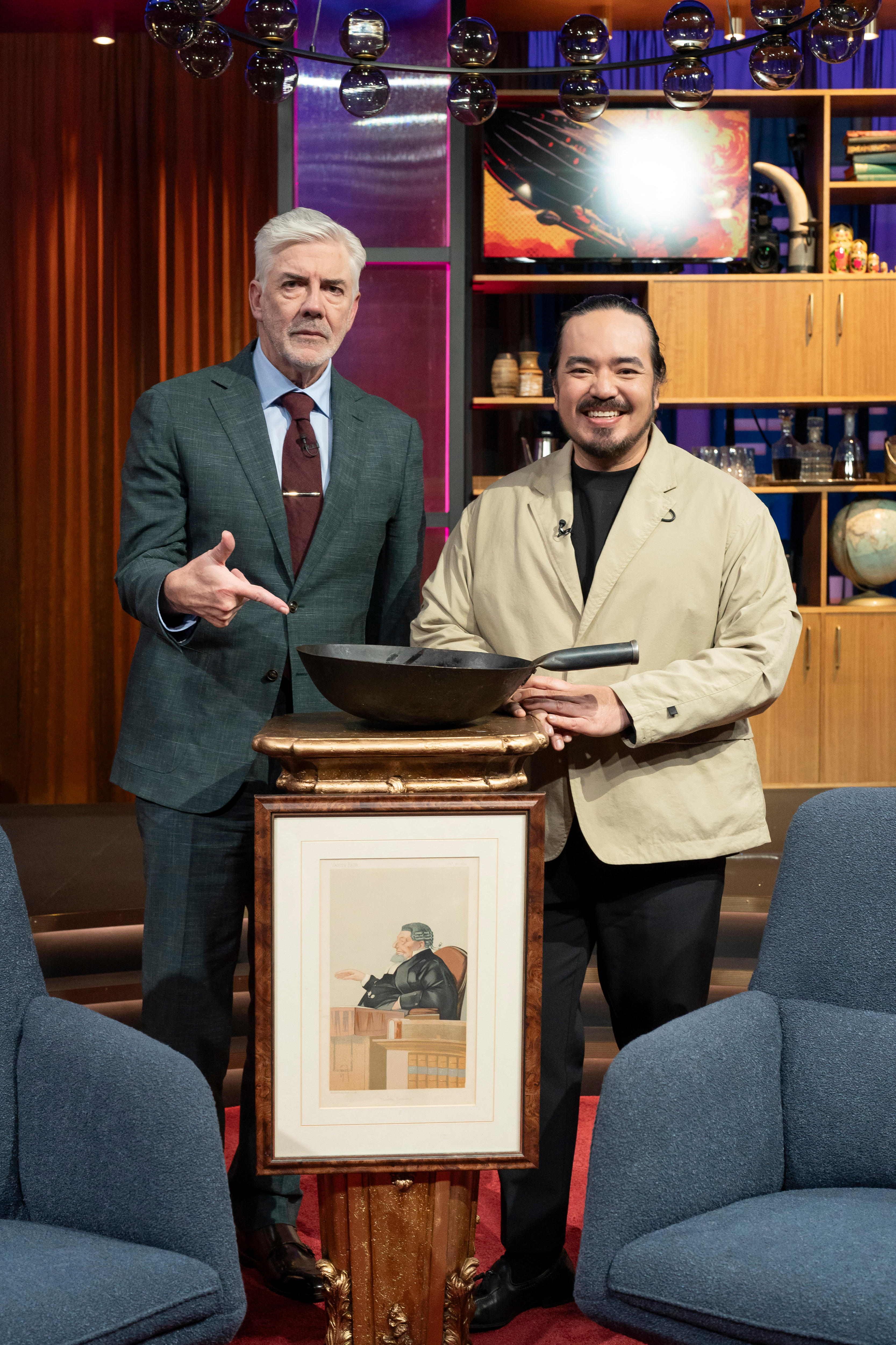 Adam Liaw and Shaun Micallef stand with Adam's ancestor portrait and wok