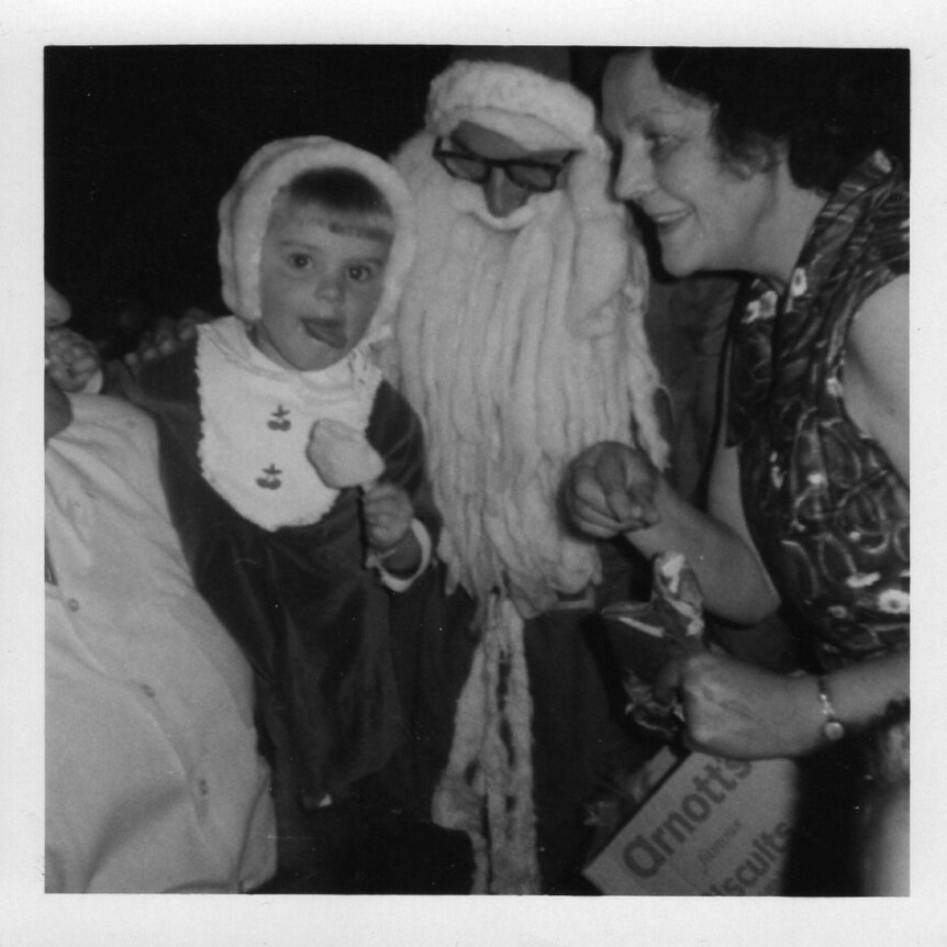 a black and white photo of santa and a kid smiling at the camera