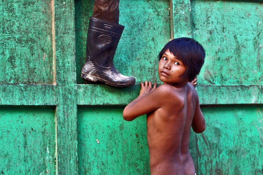 A boy scales a bin at a Cambodian rubbish dump