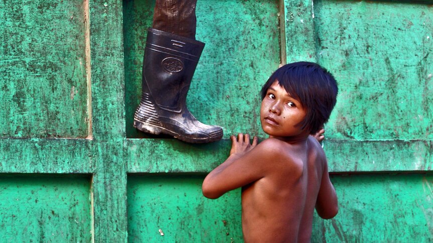 A boy scales a bin at a Cambodian rubbish dump