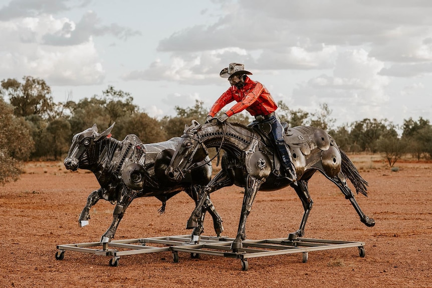 Two metal sculptures, one of a small bullock being chased by a cowboy atop a horse, all made of scrap metal