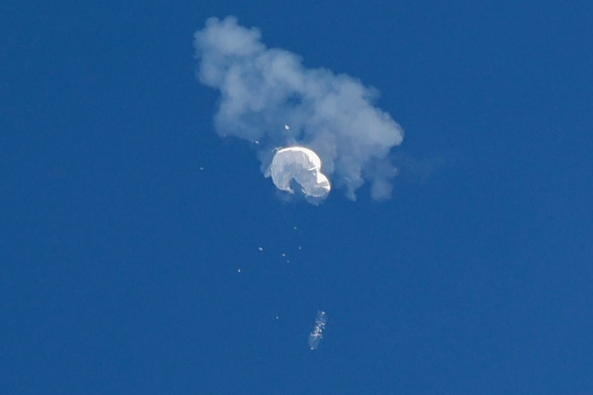 A balloon high up in the atmosphere bursts in a cloud of smoke.