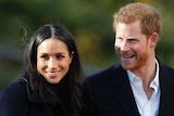 Prince Harry and his wife Meghan smile as they look away from the camera.
