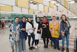 Seven women standing side by side at the airport