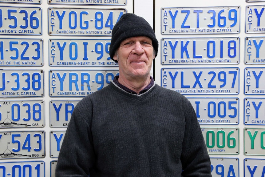 Pablo Serazio stands in front of some of the ACT number plates he has in his collection.