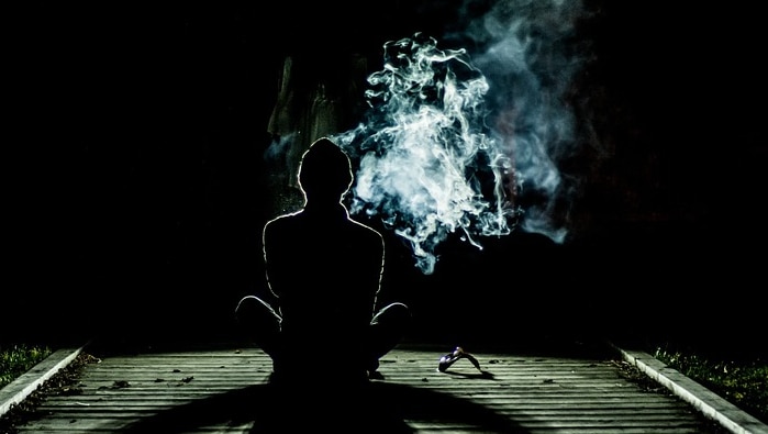 Silhouetted person with illuminated cloud of smoke.