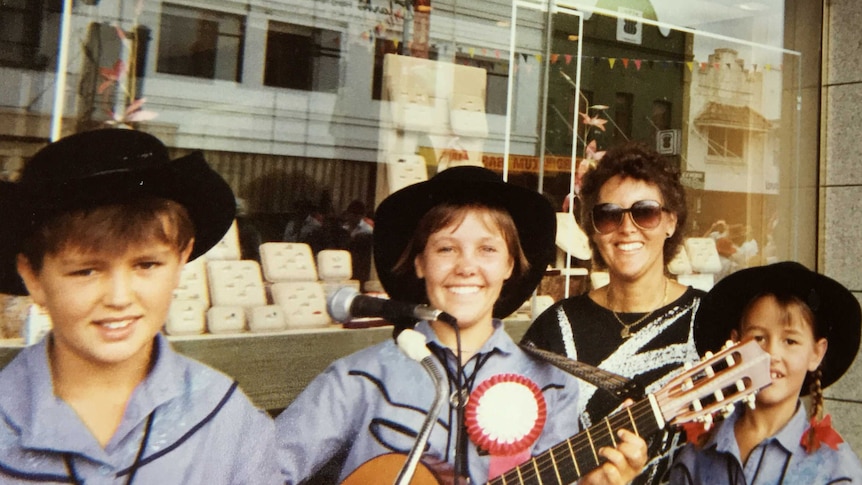 Three young buskers (including Felicity Urquhart) and a mother pose for a photo outside a jewellery store in Tamworth.